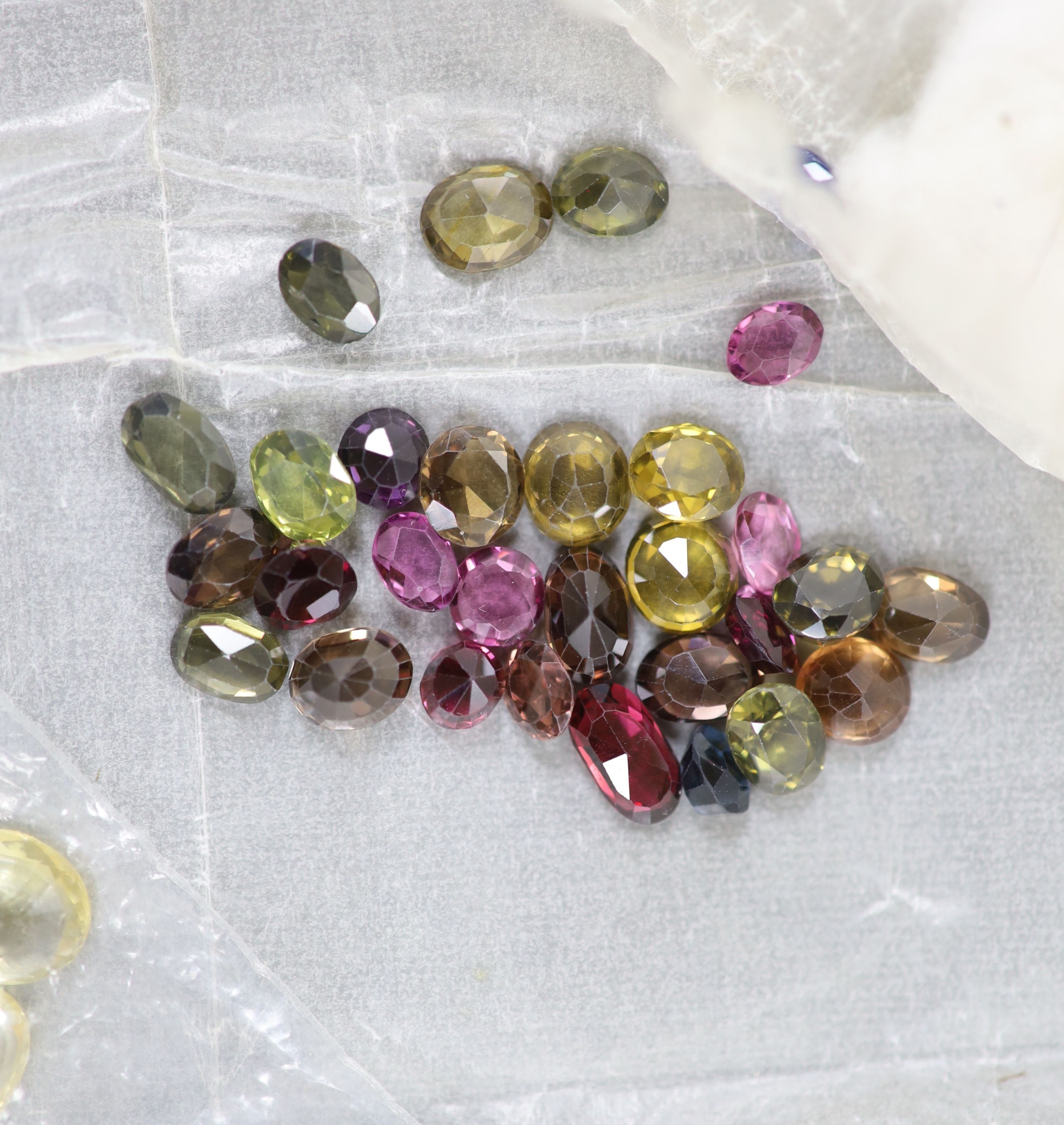 A quantity of assorted loose cut gemstones including sapphires, aquamarine, citrine and tourmalines.